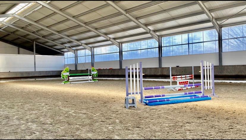 Reithalle bei ML Stables mit Springhindernissen